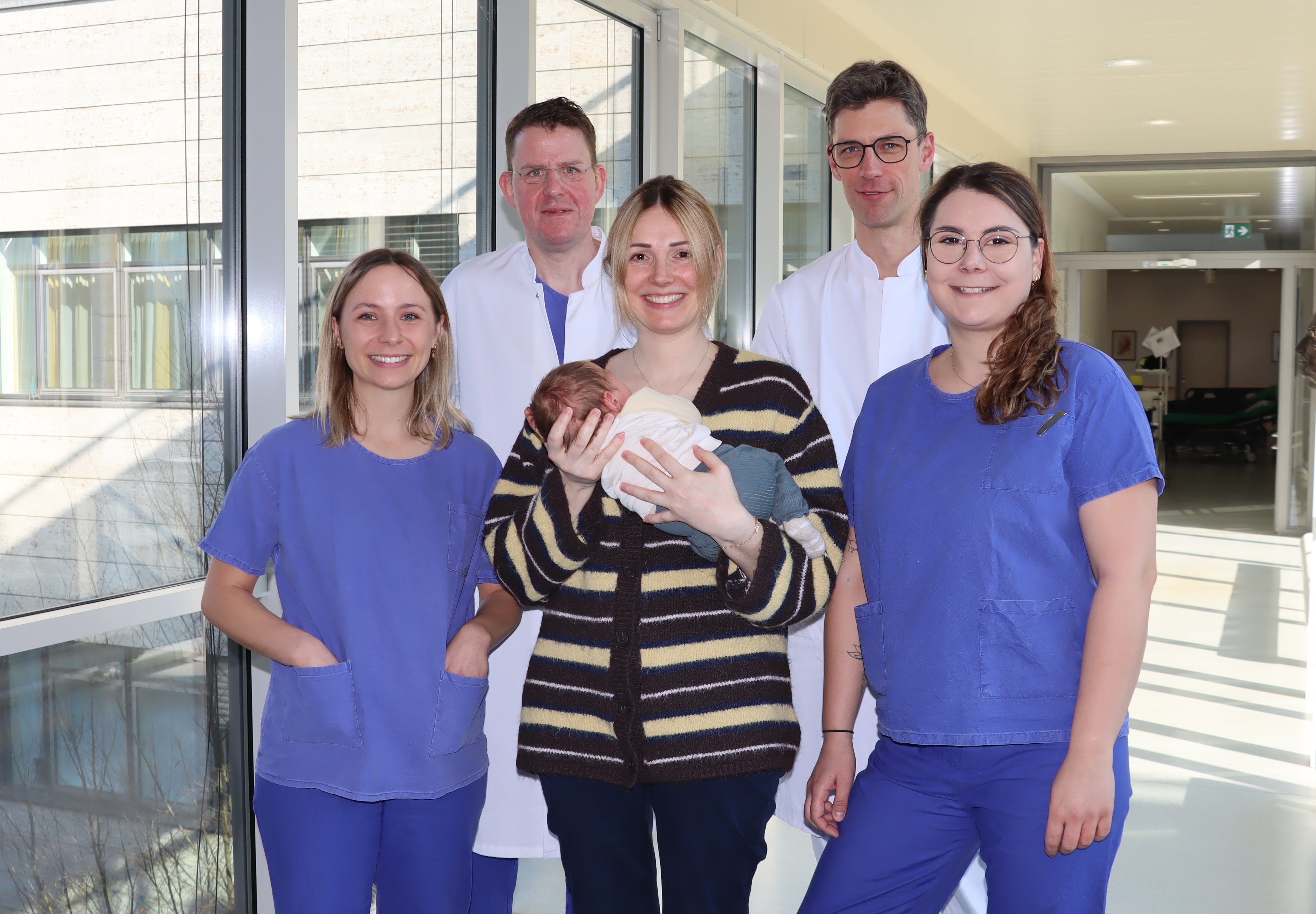 Gruppenfoto des Behandlungsteams mit Mutter Antonia Krißmer und Sohn Levi. Neben ihnen stehen die Anämie Nurses Lisa Eberle (links) und Karina Reinhard, dahinter Prof. Dr. Peter Kranke (links) und Prof. Dr. Patrick Meybohm. © Annika Wolf / UKW