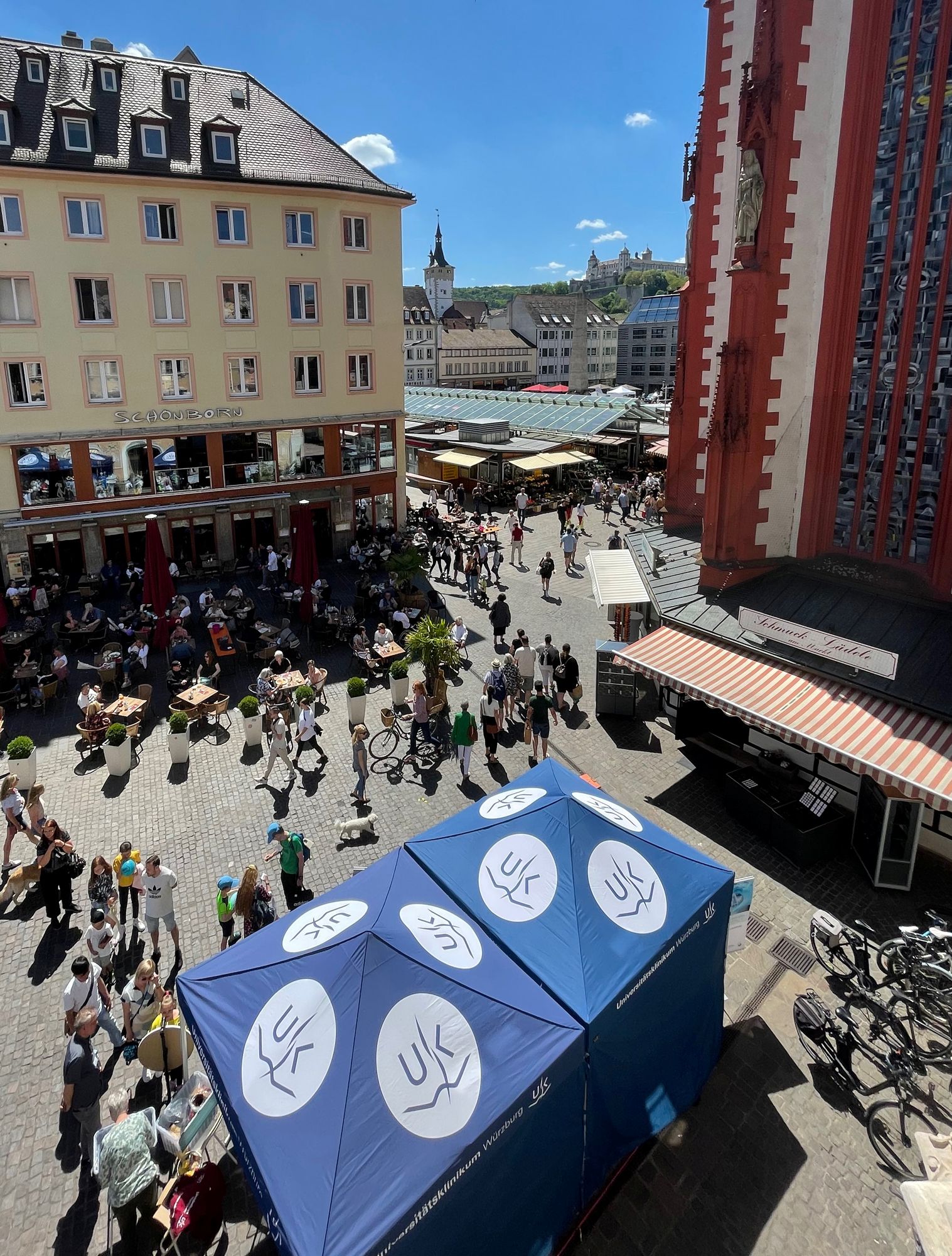 Stand des Uniklinikums mit blauen Pavillons, die mit dem UKW-Logo bedruckt sind, auf dem unteren Markt in der Würzburger Innenstadt