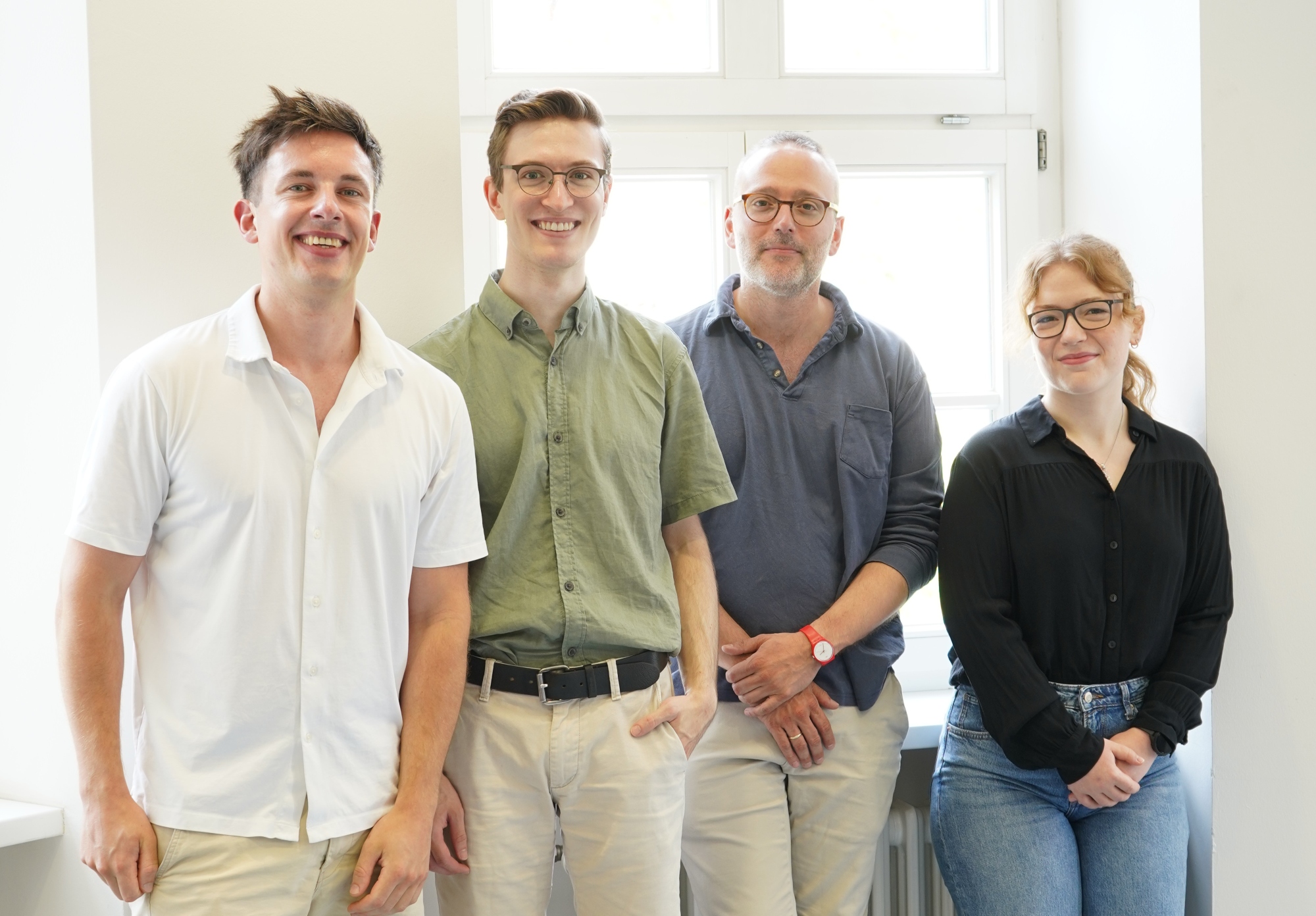Die drei Männer und die Doktorandin stehen nebeneinander im Raum des Instituts für Allgemeinmedizin. 