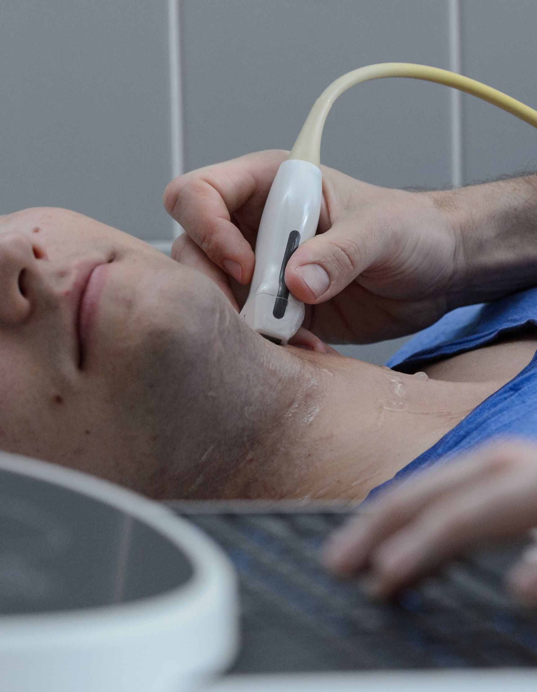 Bei einem Mann wird eine Dopplersonographie am Hals durchgeführt.