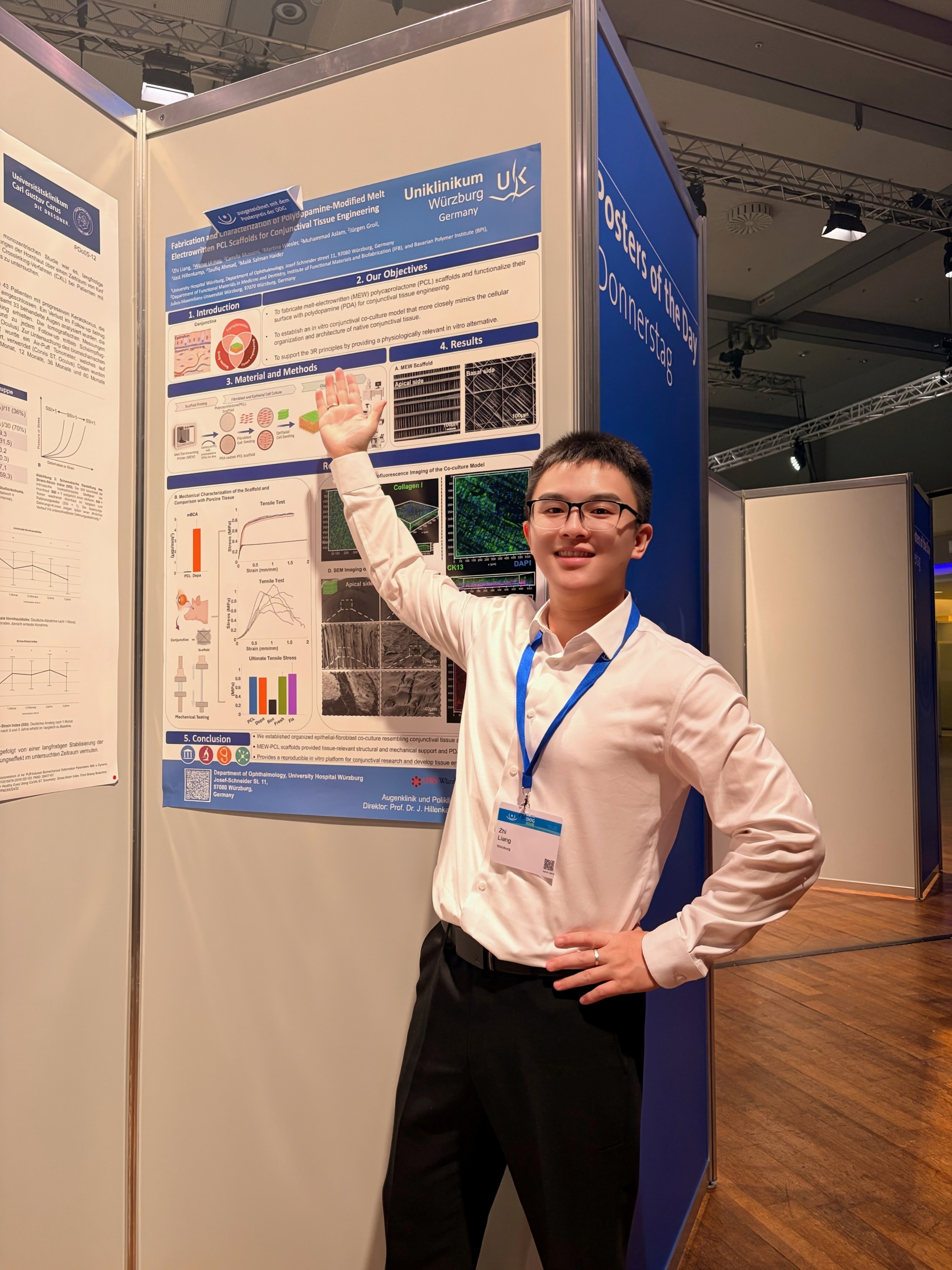 Zhi Liang präsentiert sein Wissenschaftsposter auf dem DOG-Kongress - er steht vor dem Ausdruck an der Posterwand und hält Arm in die Höhe 