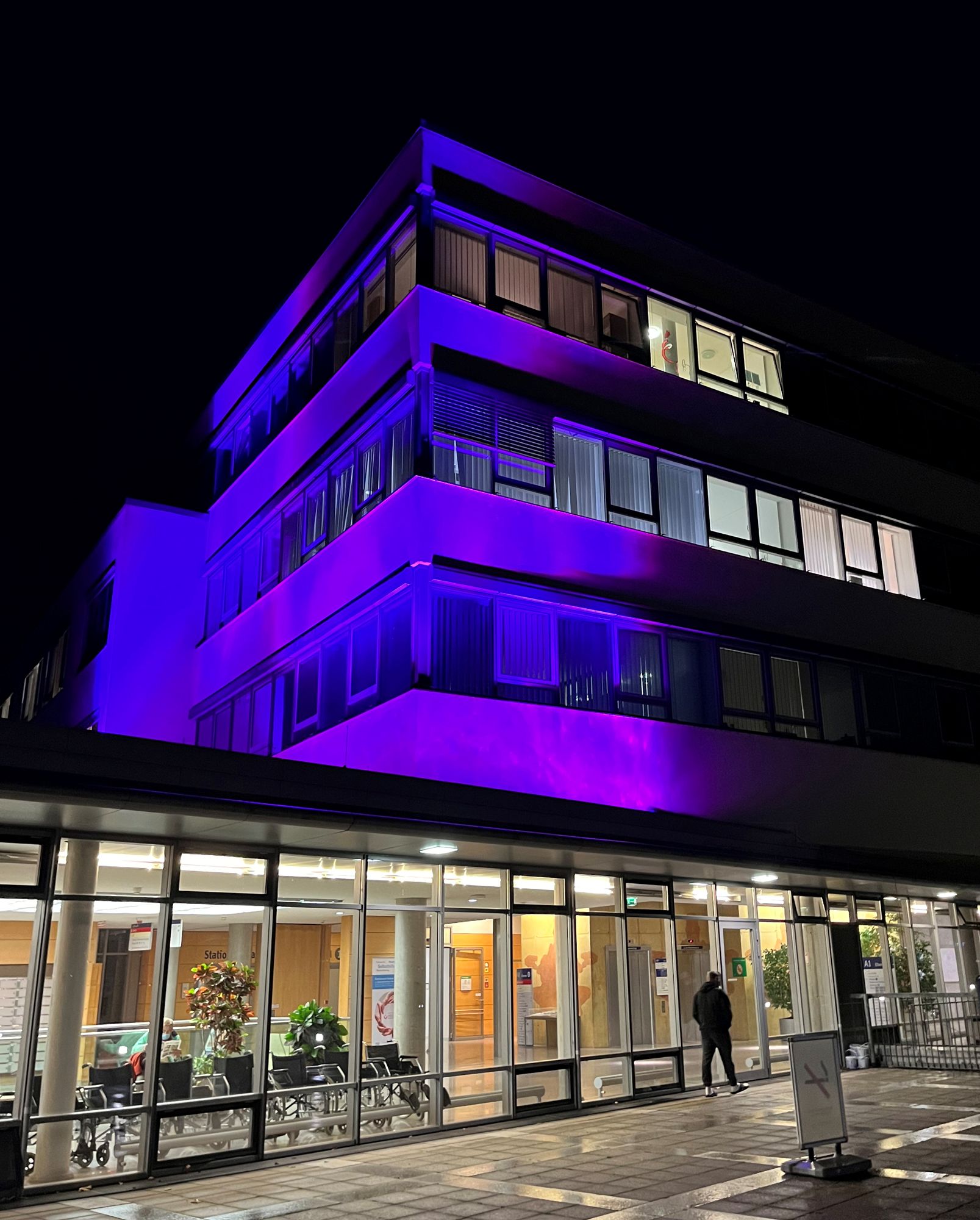 ZOM-Gebäude bei Nacht das violett angestrahlt wird.