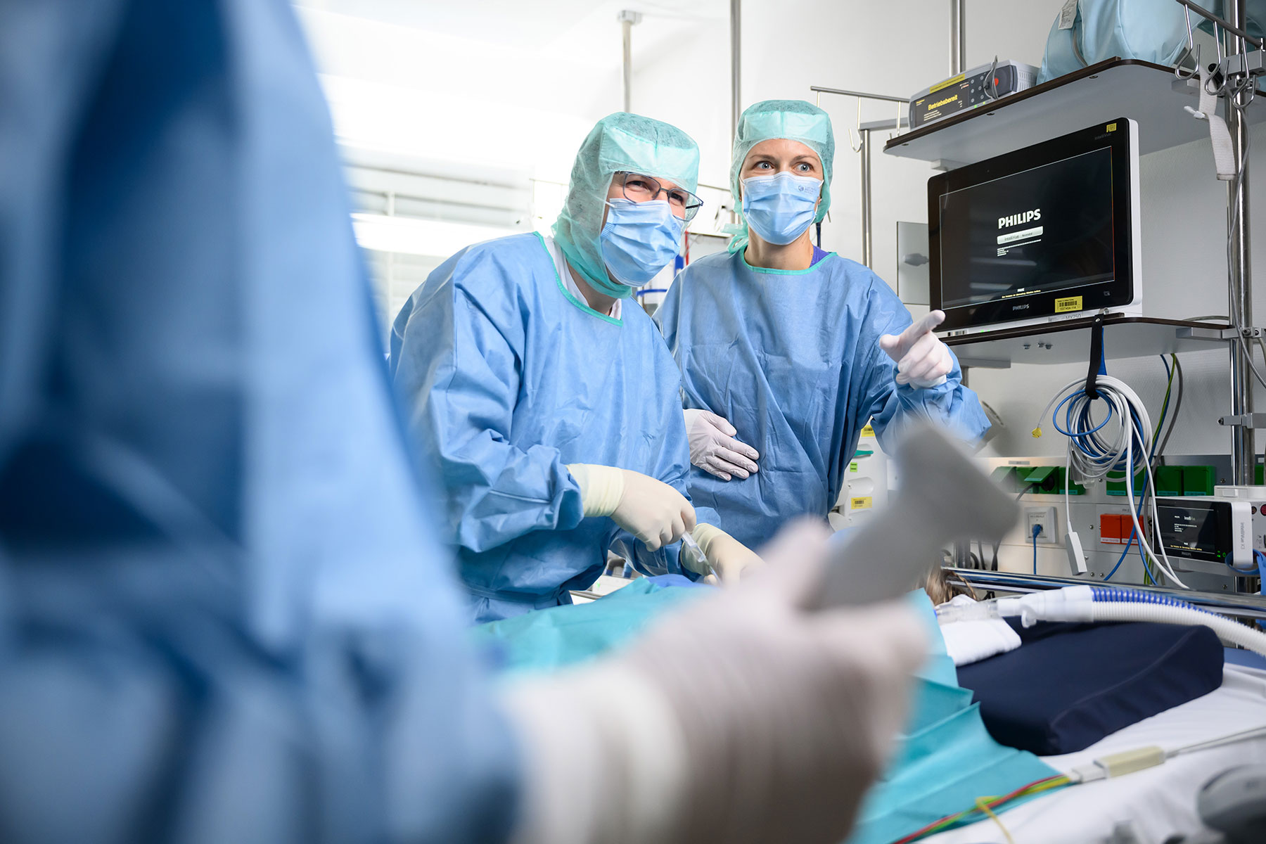 Zwei medizinische Fachkräfte in Funktionskleidung führen eine Untersuchung an einem Kind durch