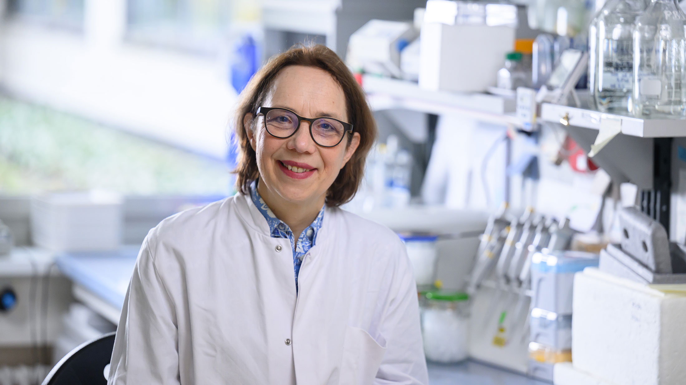 Porträt von Prof. Heike Rittner im weißen Kittel in einem Labor des Universitätsklinikums Würzburg.